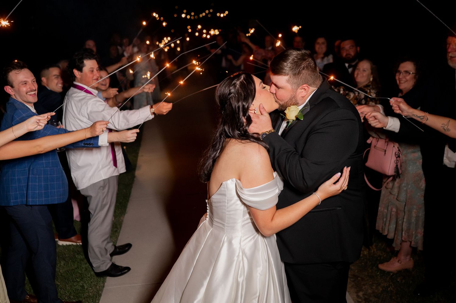 Wedding guests dancing and celebrating under twinkling lights at night.