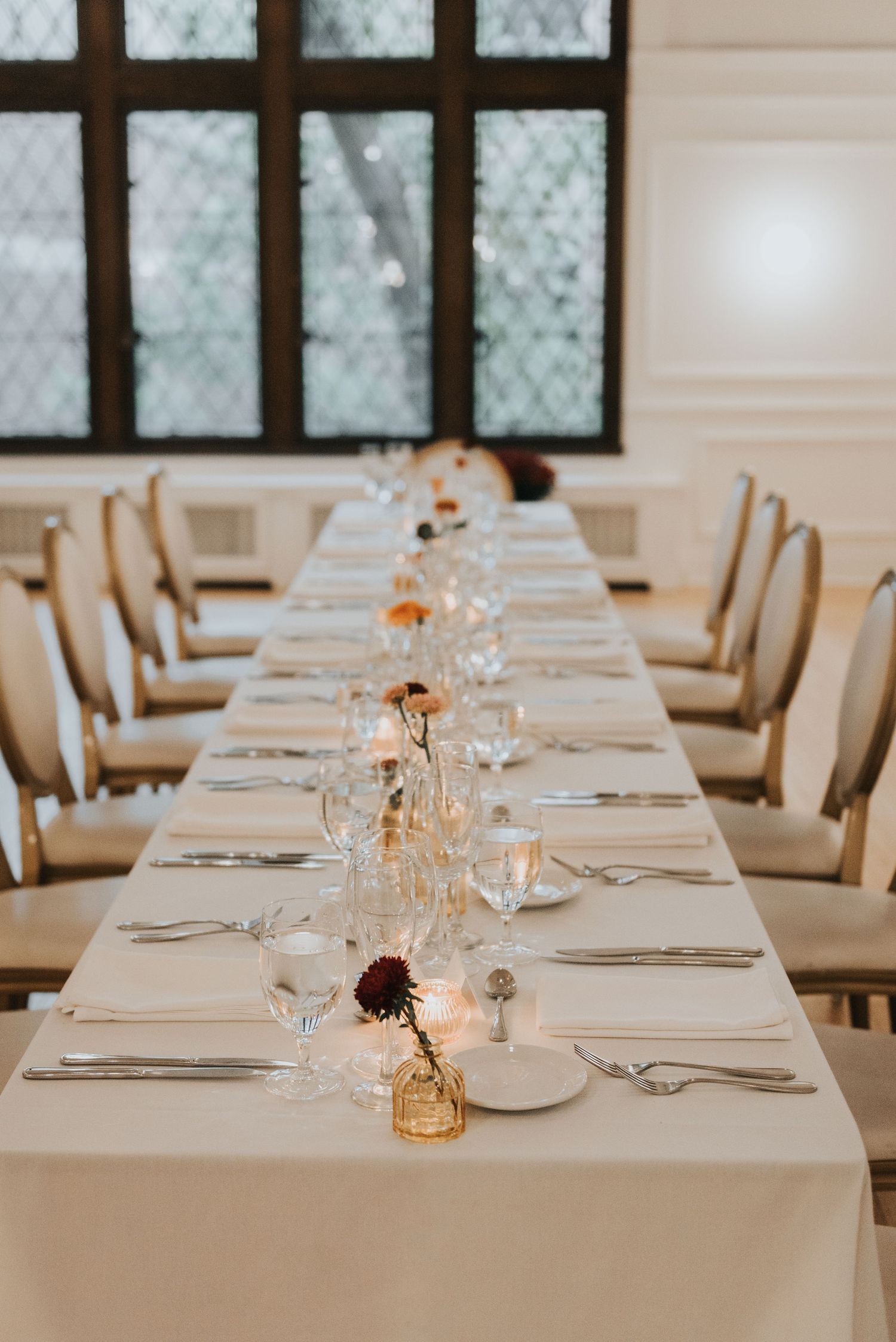 Elegant white dining tables set with glassware and place settings in a bright modern restaurant interior.