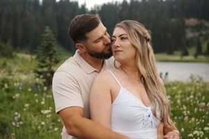 Intimate couple embracing in a mountain meadow surrounded by colorful summer wildflowers.
