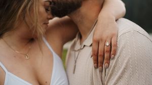 A couple embraces in a romantic moment against a natural mountain lake backdrop.