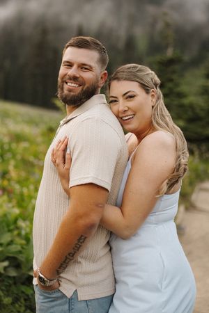 A tender moment shared between a couple in cream and white attire by a lake.