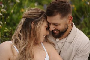 A couple shares an intimate moment together while walking through a lush garden setting.