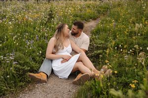 Couple shares tender moments while sitting in a blooming wildflower meadow.