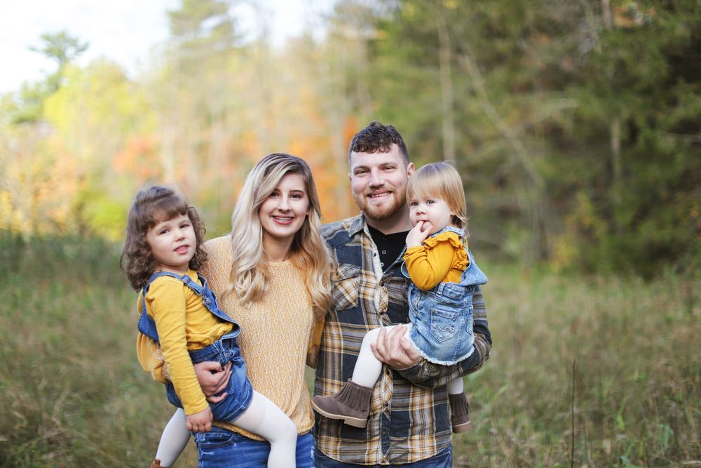 Natural outdoor setting with fall foliage and pine trees in the background.