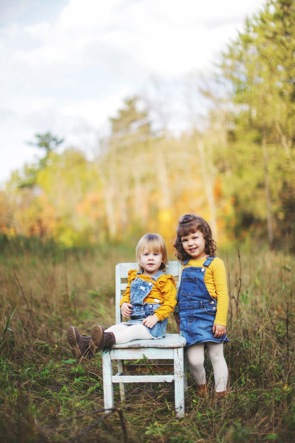 Small blue wooden bench placed in tall grass during autumn.