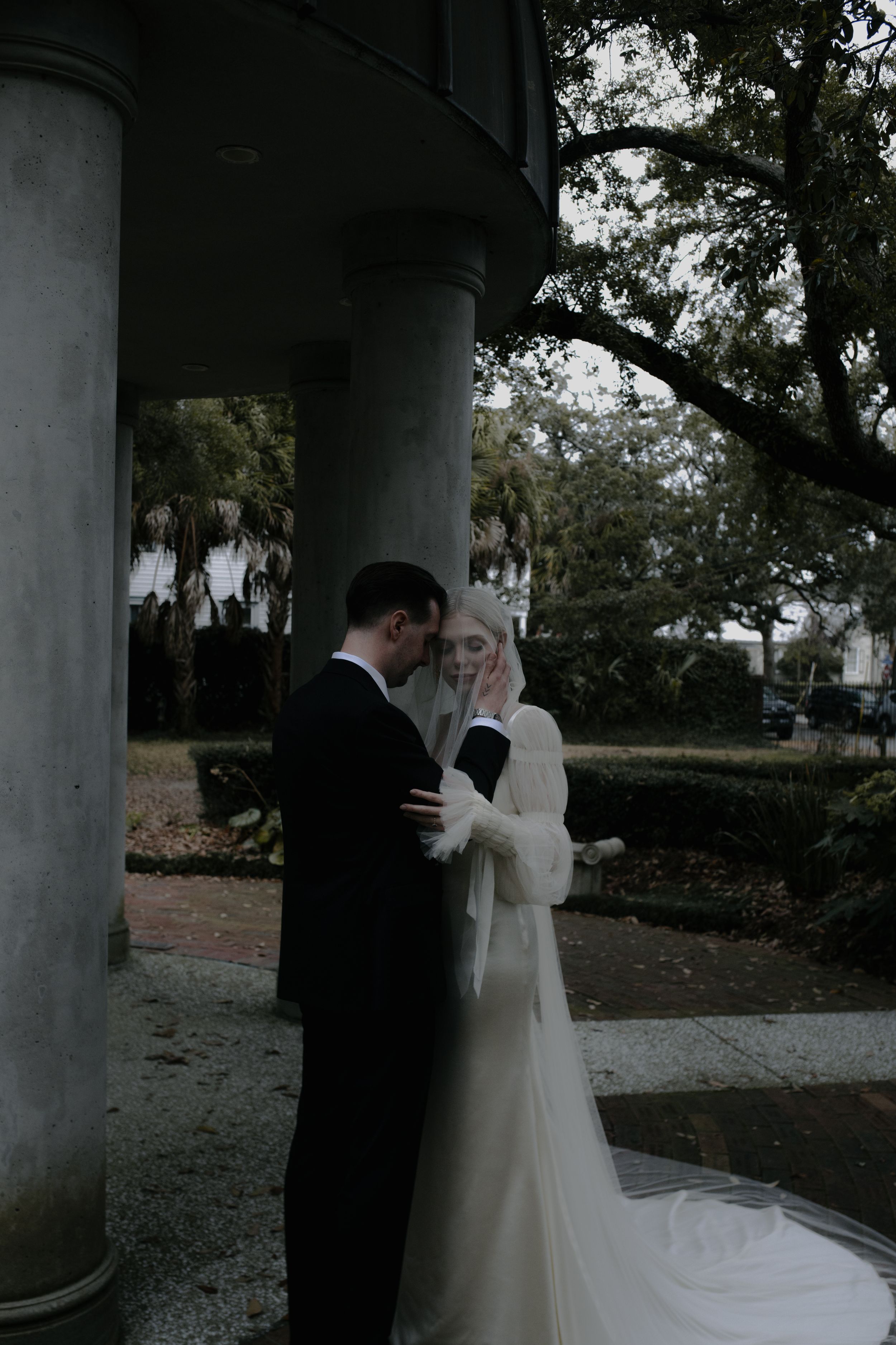 A romantic first look sequence between newlyweds under a covered outdoor walkway.