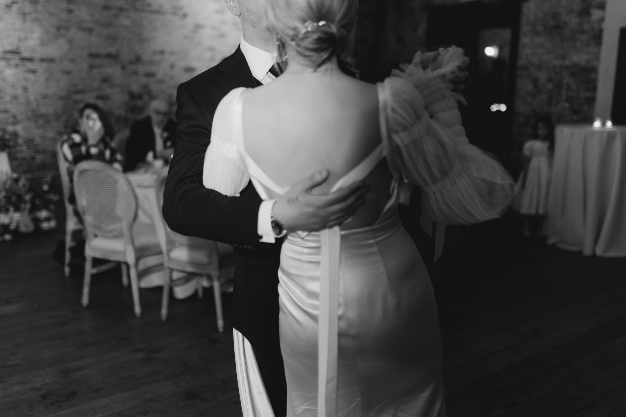 A couple in wedding attire dancing together in an intimate moment at their reception.