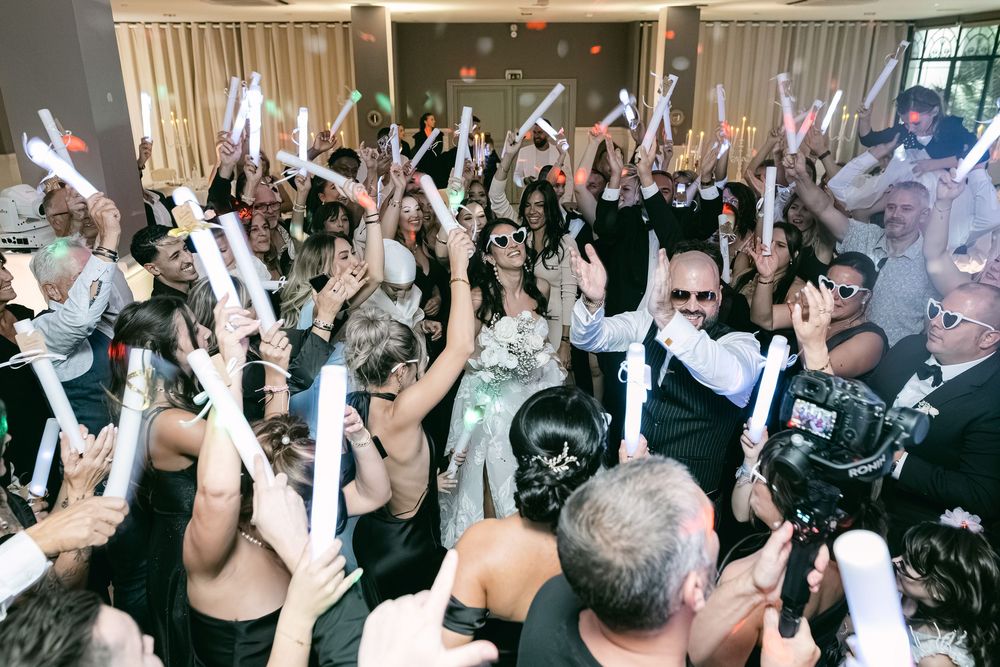 Crowd of wedding guests dancing with arms raised on a dance floor during a celebration.