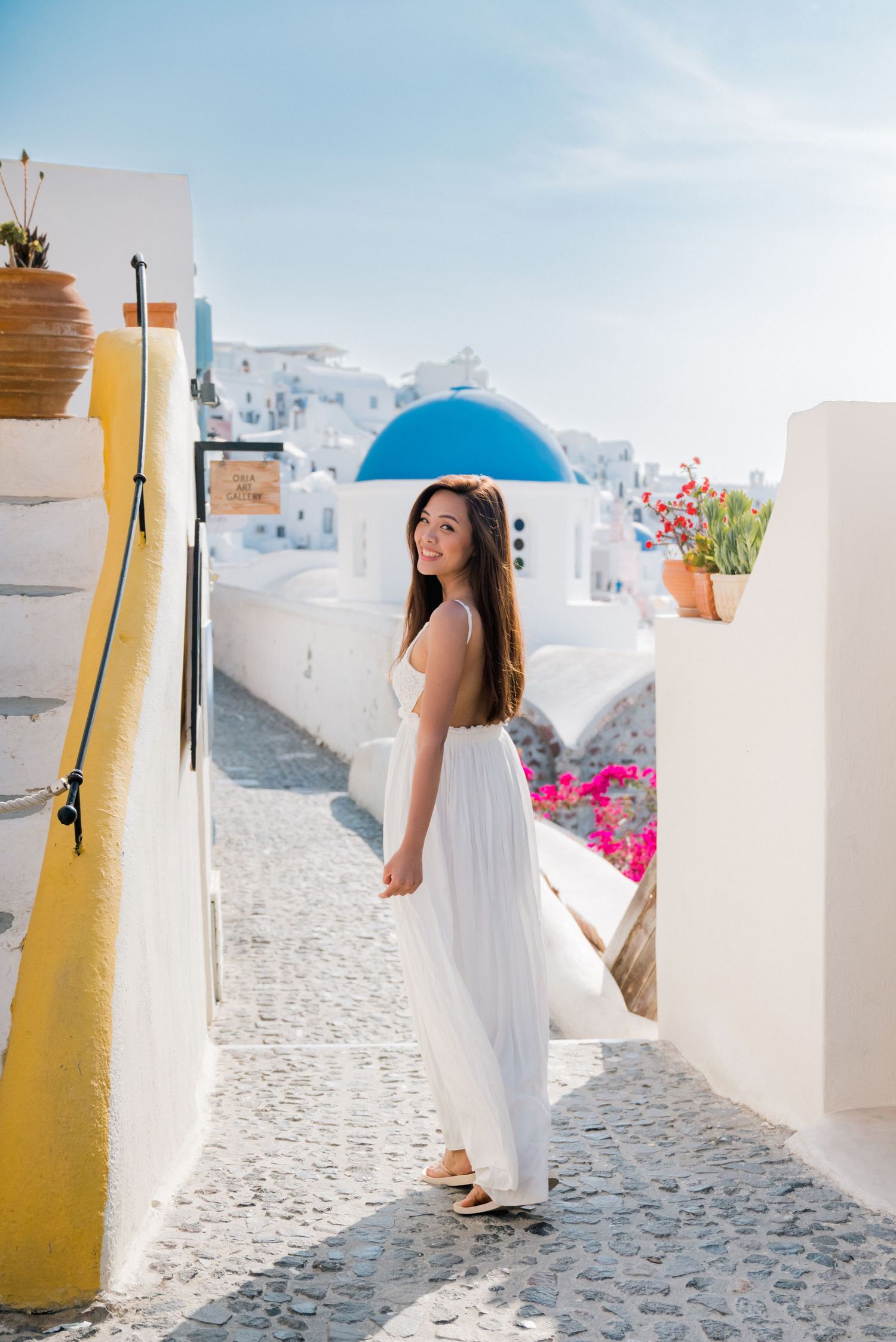 A couple sits together overlooking a scenic coastal mountain landscape with blue water and clear skies in Santorini