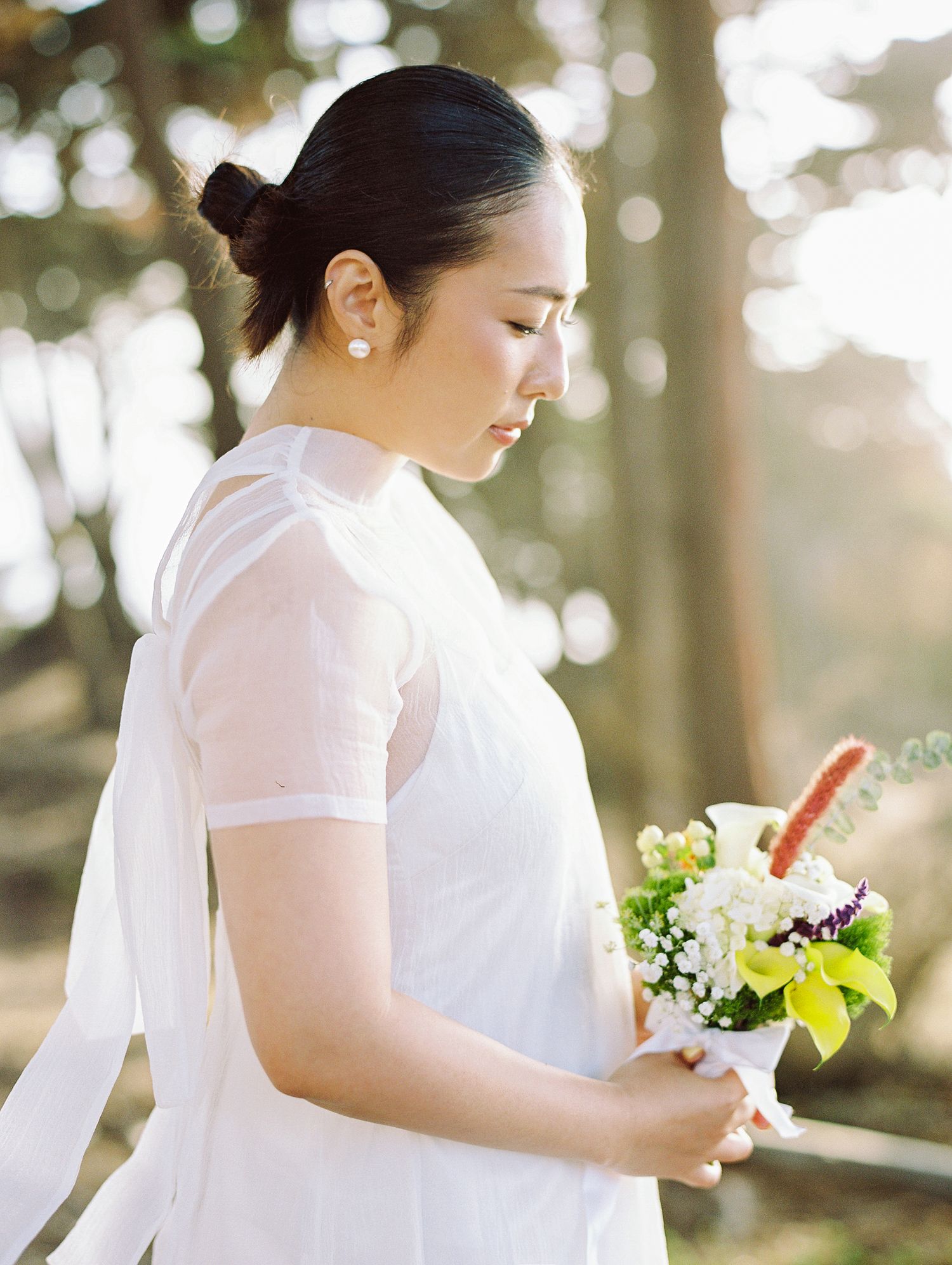 Romantic wedding ceremony sequence showing bouquet exchange with white flowers and greenery against blurred forest backdrop.