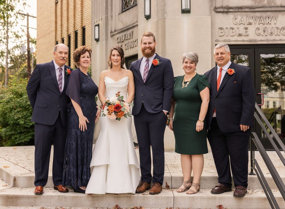 Wedding party poses in formal attire outside a stone building with classic architectural details. Columbus Ohio.