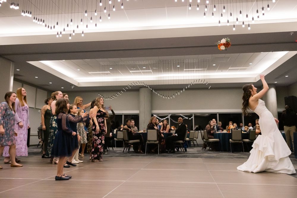 Wedding guests dance together on a ballroom floor during a reception celebration under elegant chandelier lighting. Bob crane event center
