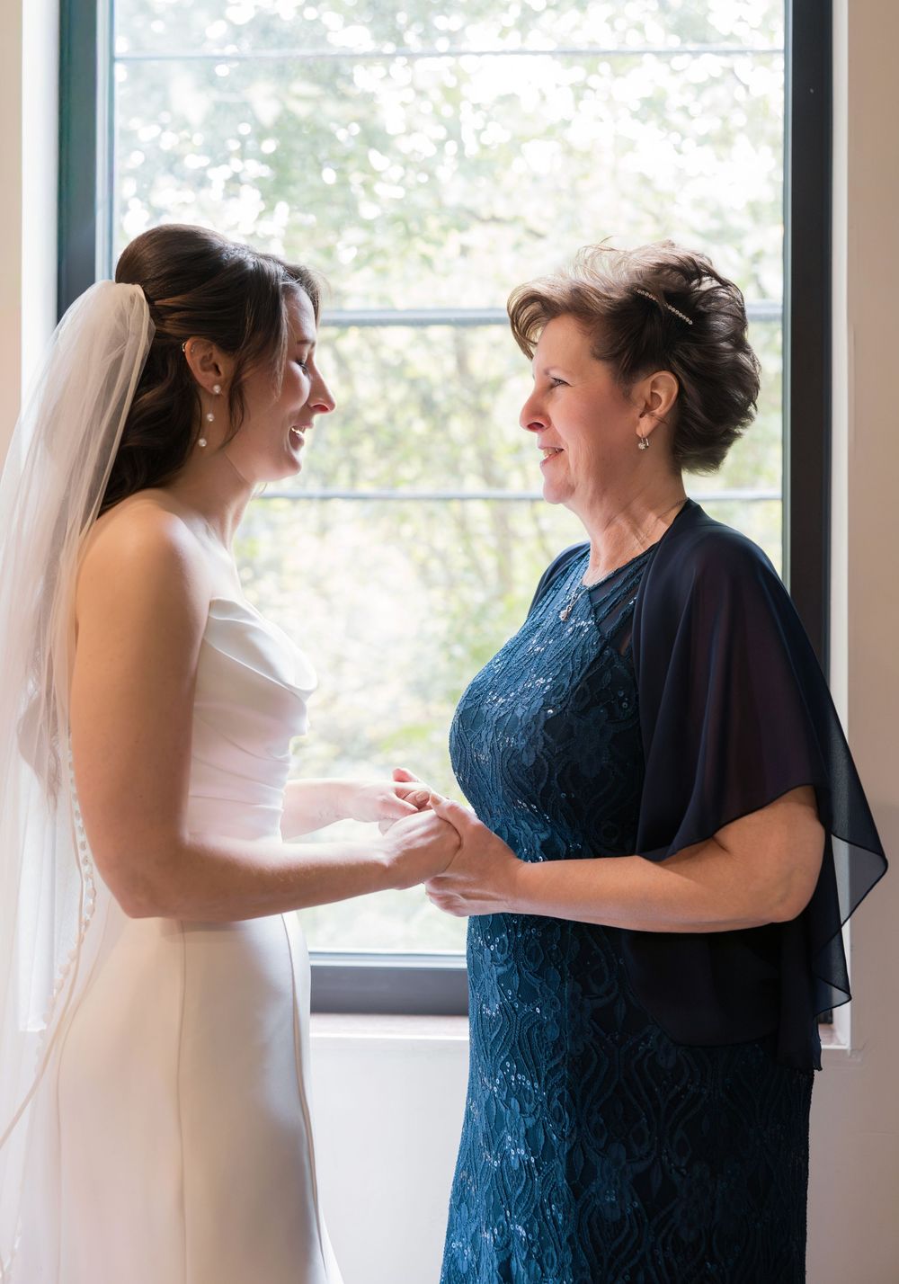 A tender moment between a bride in white and a woman in navy blue as they share an emotional embrace. Columbus Wedding