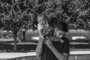 A touching black and white photo of a father holding his baby in a park setting. family session kimbell art museum fort worth texas