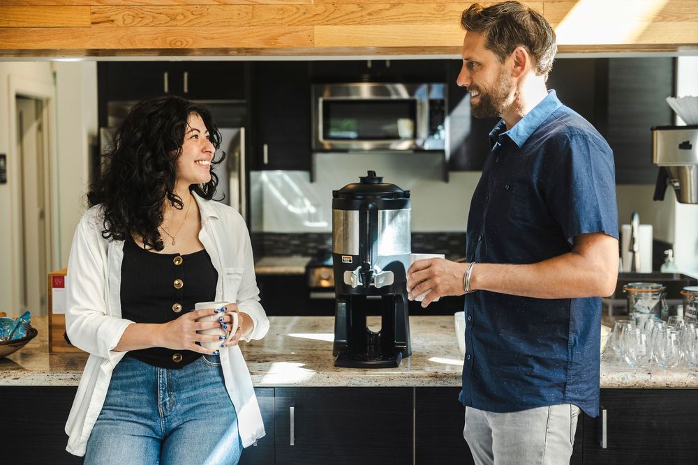 People chatting and working in a modern office space with wood paneling and natural light.