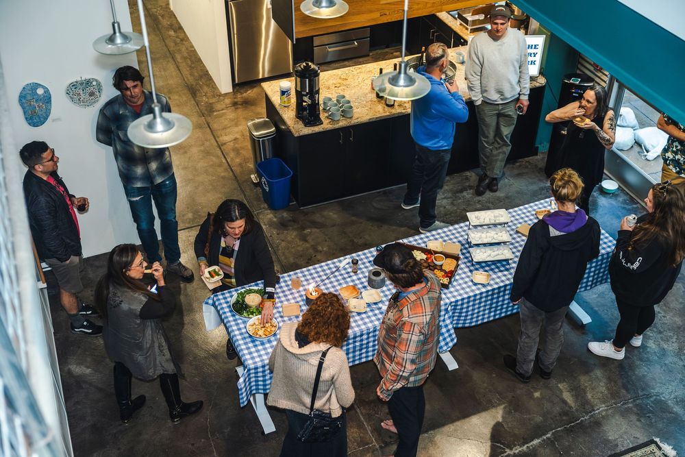 Overhead view of a busy office space with multiple workstations and people collaborating at tables.