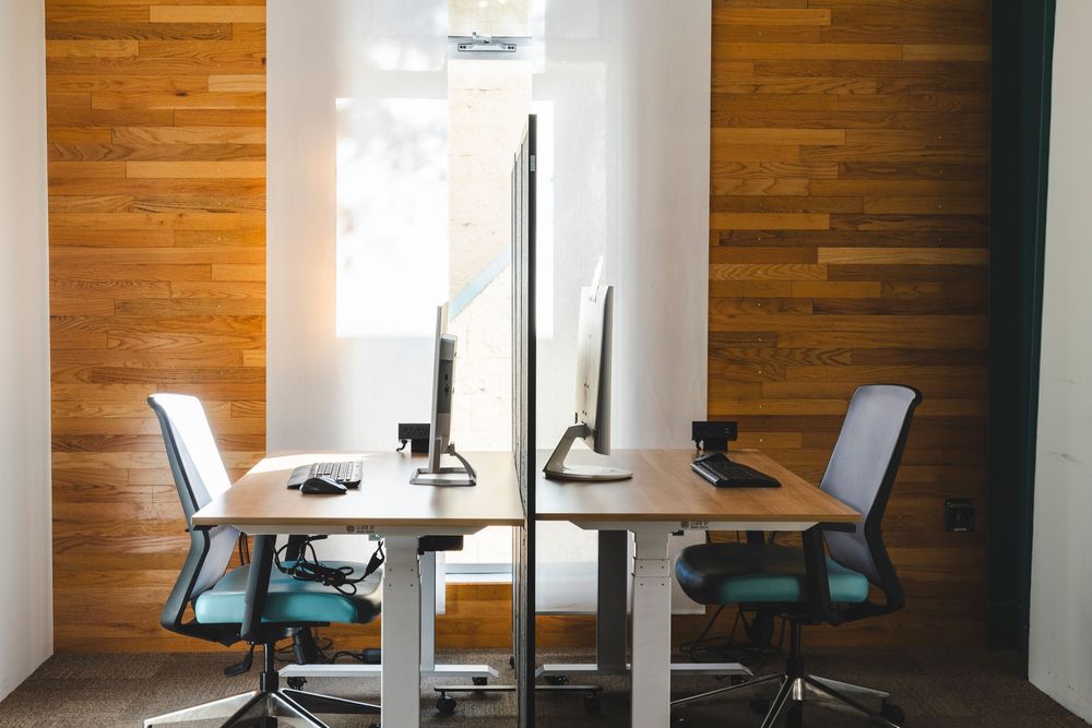 Modern office interior with wooden wall paneling and minimalist desk setups.