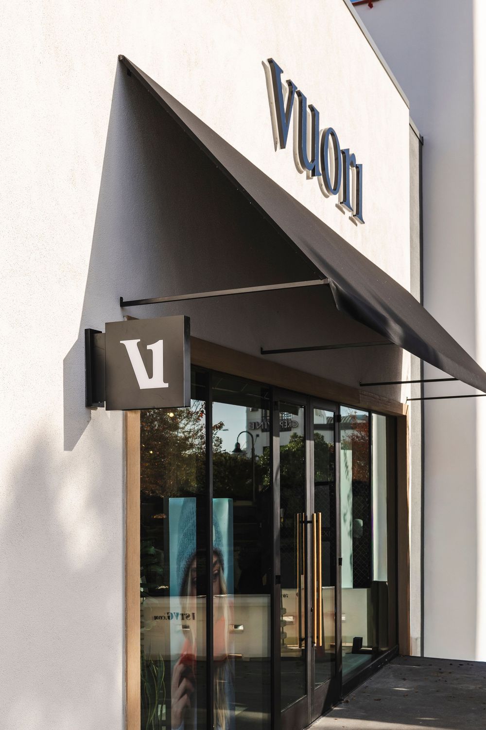 Modern storefront exterior with white walls and black awnings featuring large glass windows and clean architectural lines.