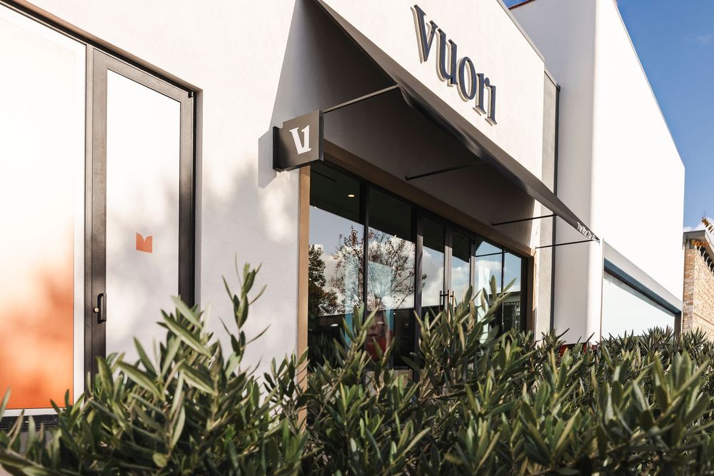 Modern white commercial building exterior with Vdot signage and landscaped bushes in front.