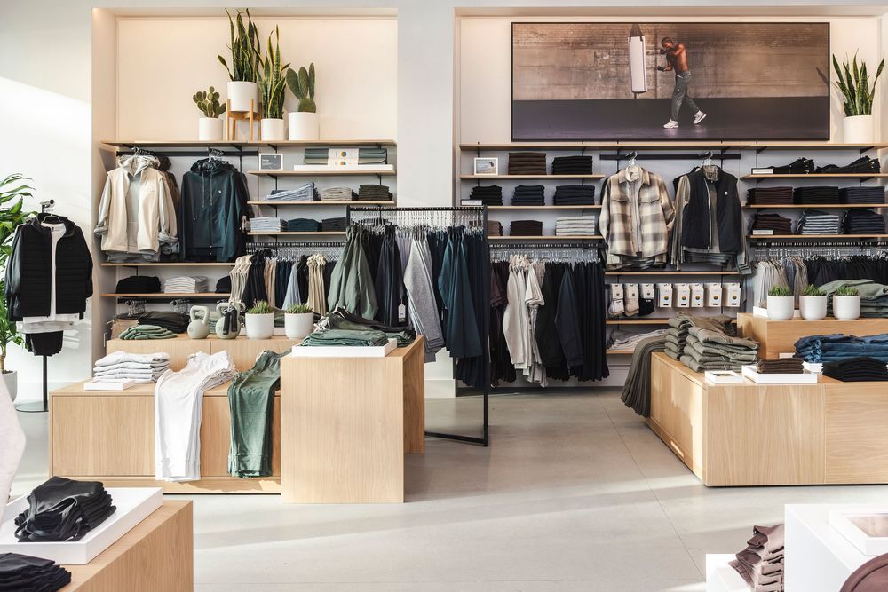 Modern retail clothing store interior with wooden displays, metal racks, and minimalist design aesthetic.