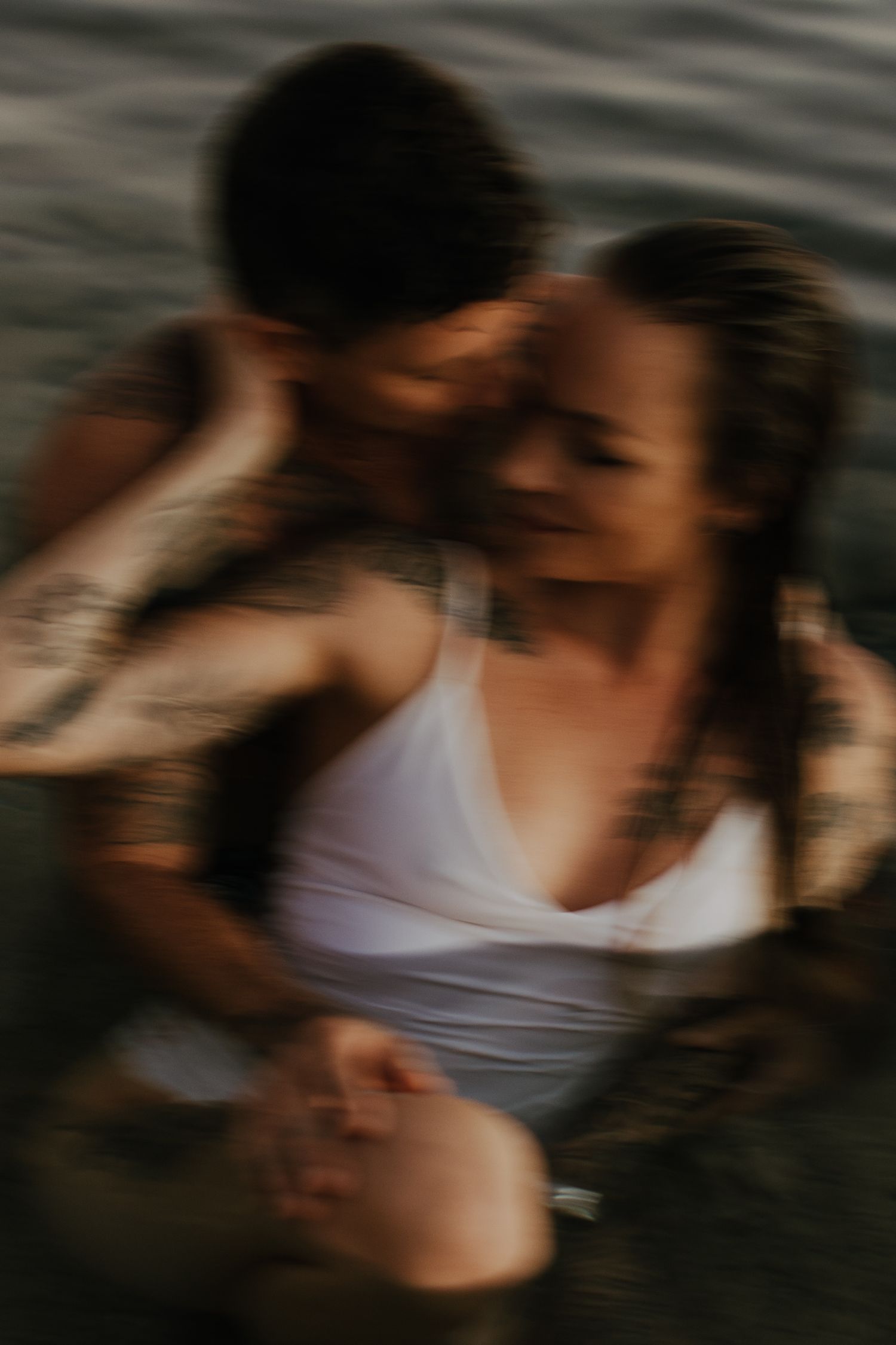 A blurred artistic sequence showing intimate moments between a couple in white clothing against a dark background.