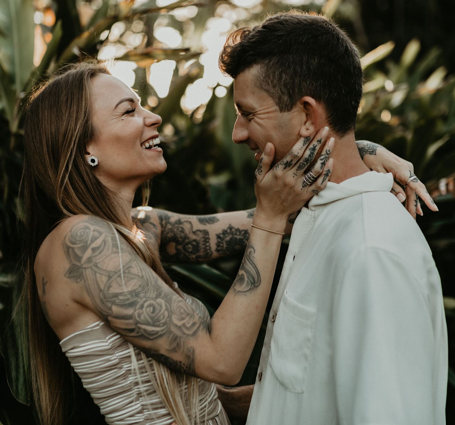 A romantic couple shares intimate moments in a lush garden setting during a photo session.