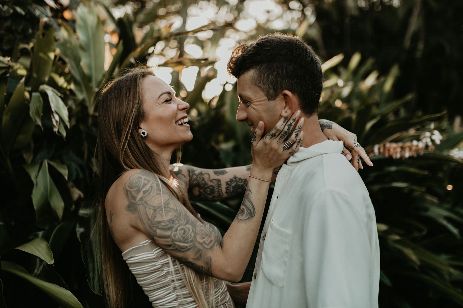 Romantic couple shares intimate moment surrounded by lush tropical greenery.