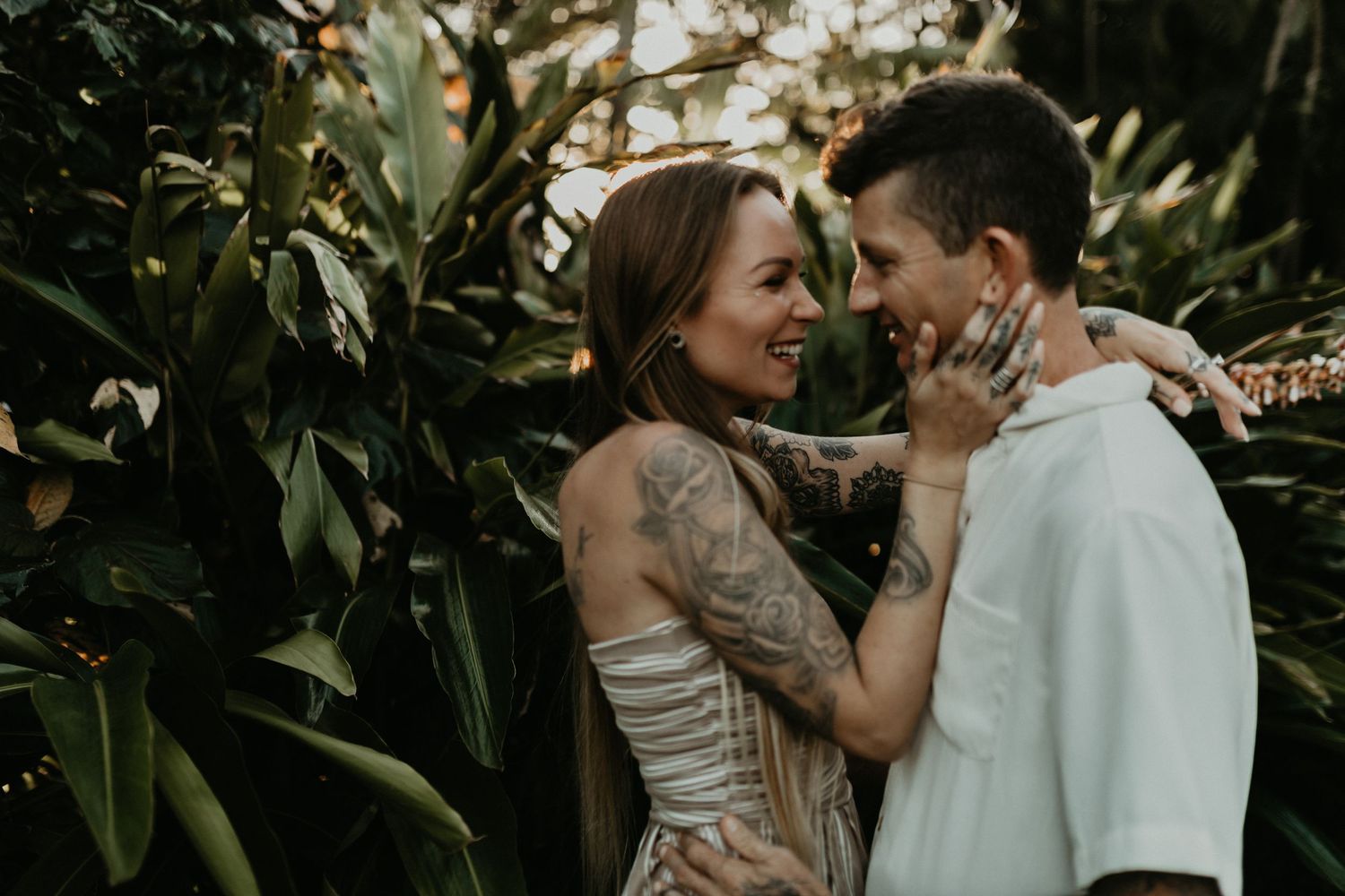 Romantic couple embracing in a lush tropical garden setting during a wedding photo session.
