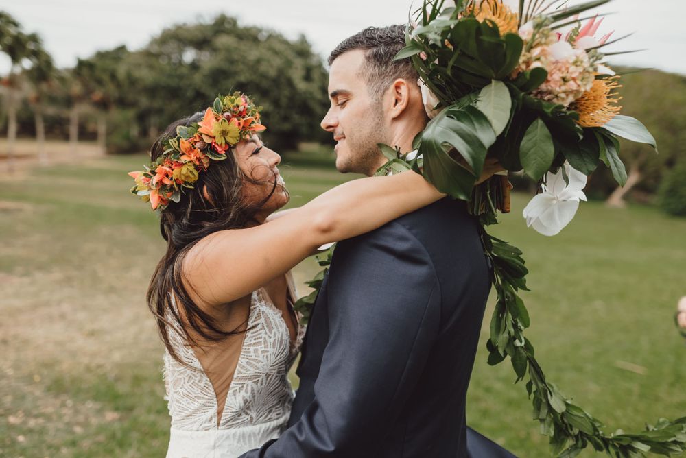 Intimate wedding portraits captured on grassy field with tropical decorations.
