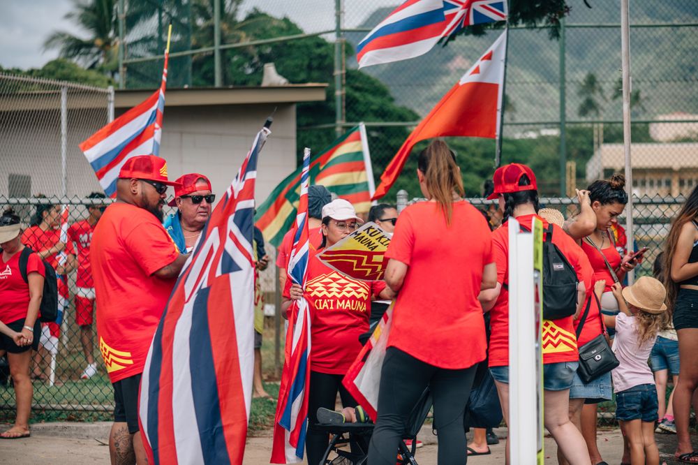 Supporters with Hawaiian state flags gather along a street during a demonstration.