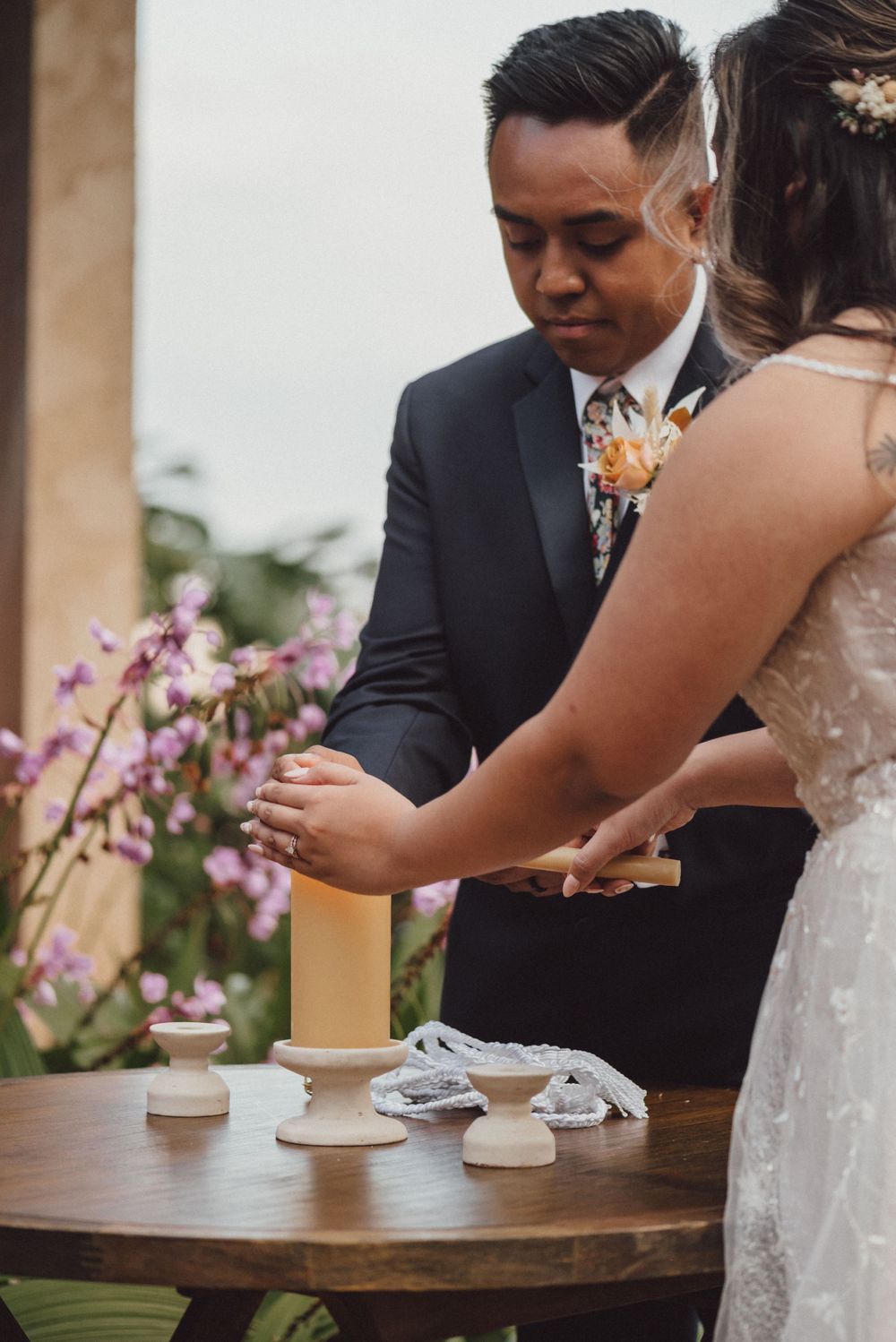 A couple participates in a unity candle ceremony at their outdoor wedding.