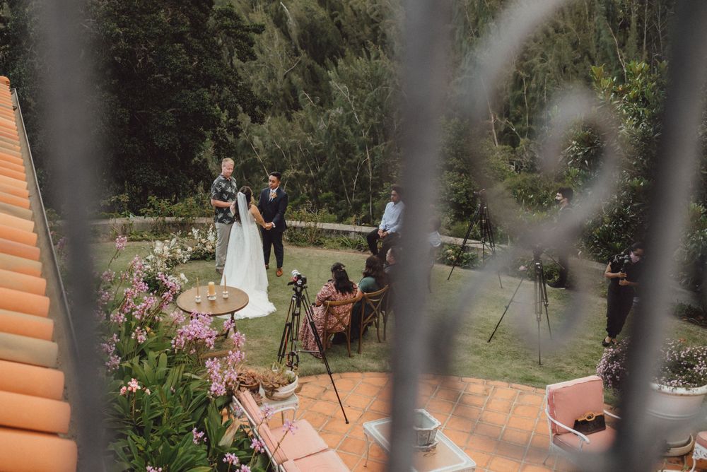 An intimate outdoor wedding ceremony viewed through decorative railings.