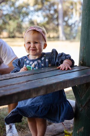 Little girl smiling while leaning on bench