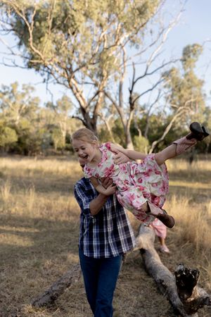 Father swinging girl around in a paddock during a professional family photo shoot
