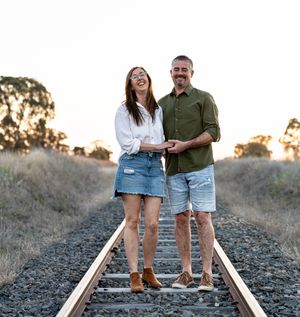 couple laughing while holding hands and walking down the railway track at family professional photo shoot