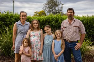 family at professional photo shoot in playground standing in front of hedge
