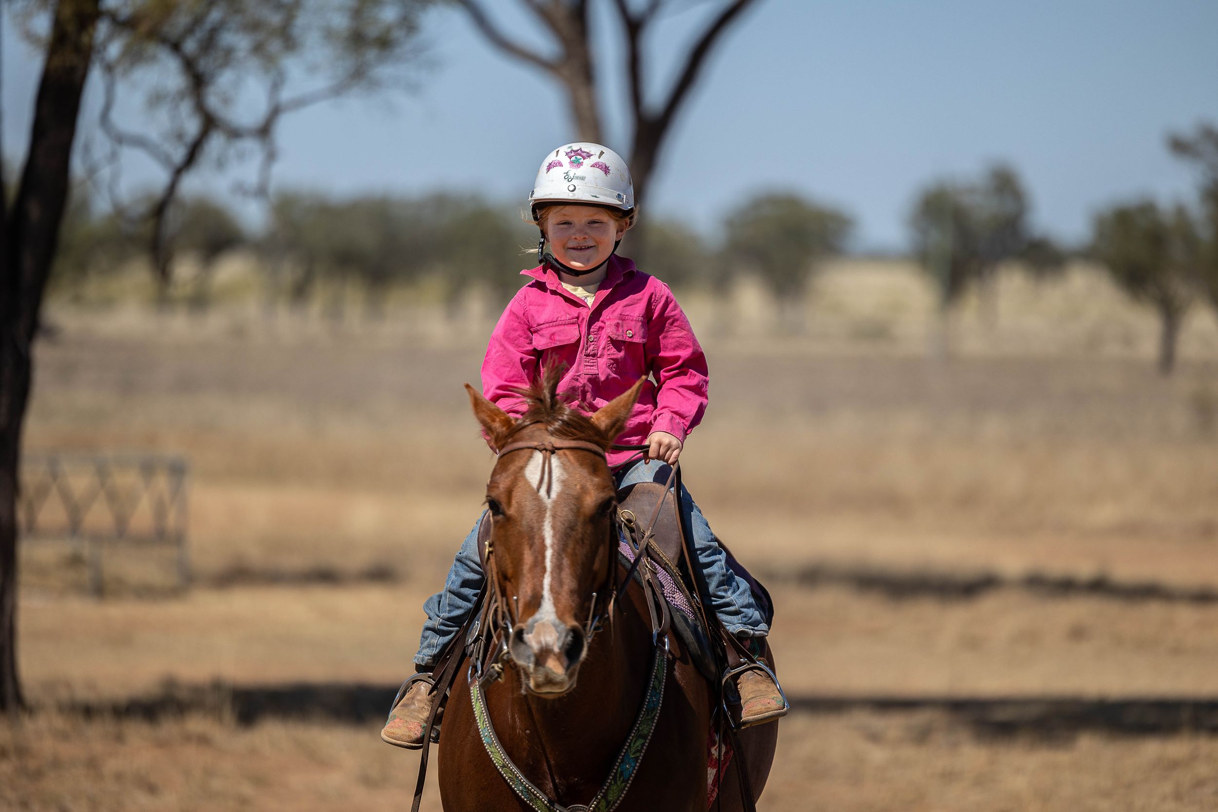 girl riding a horse and smiling on a country rustic farm