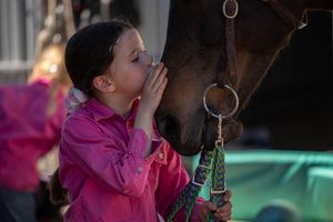 girl kissing horse on the nose on country rustic farm
