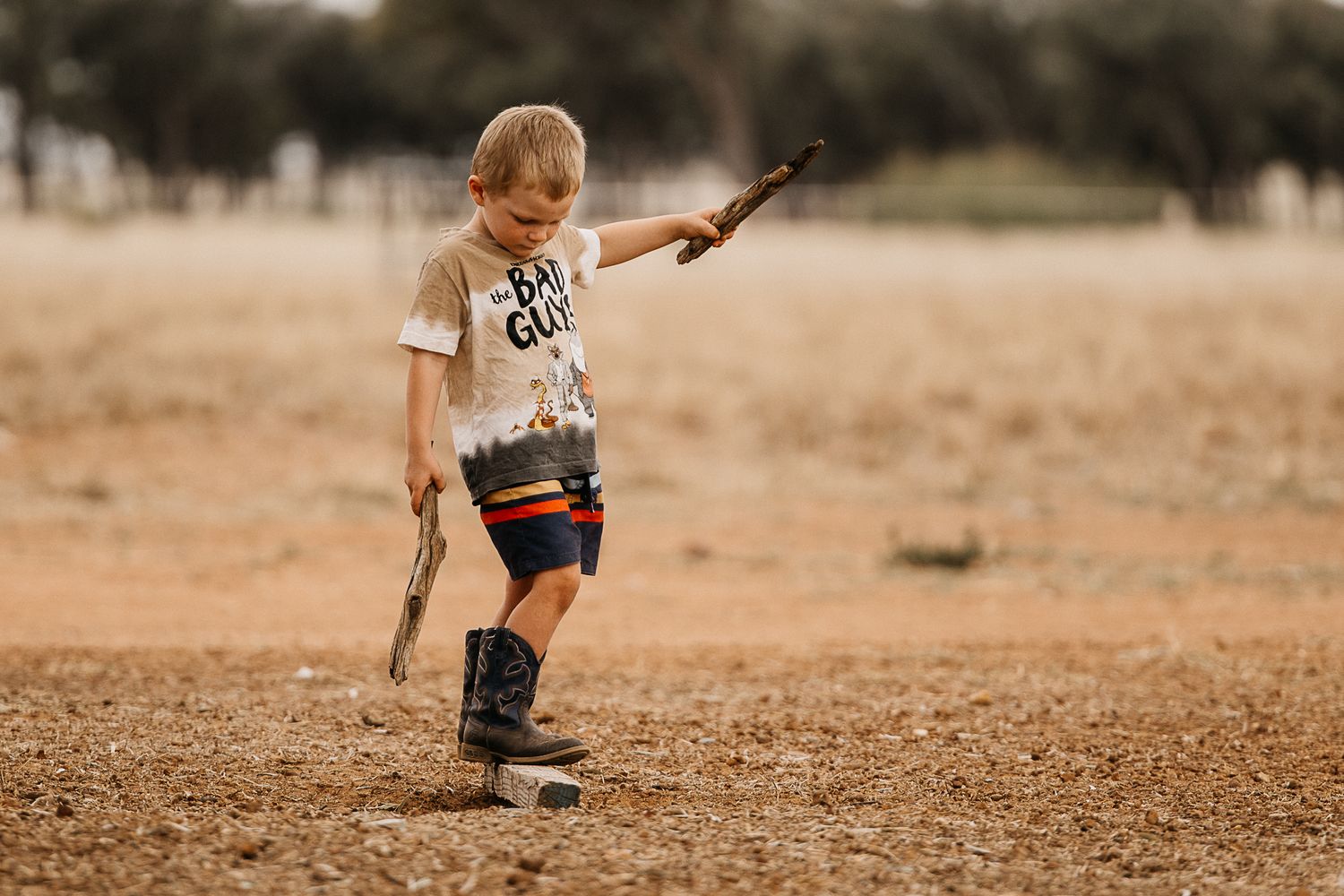 Boy walking along a stick over a hole while balancing with two other sticks
