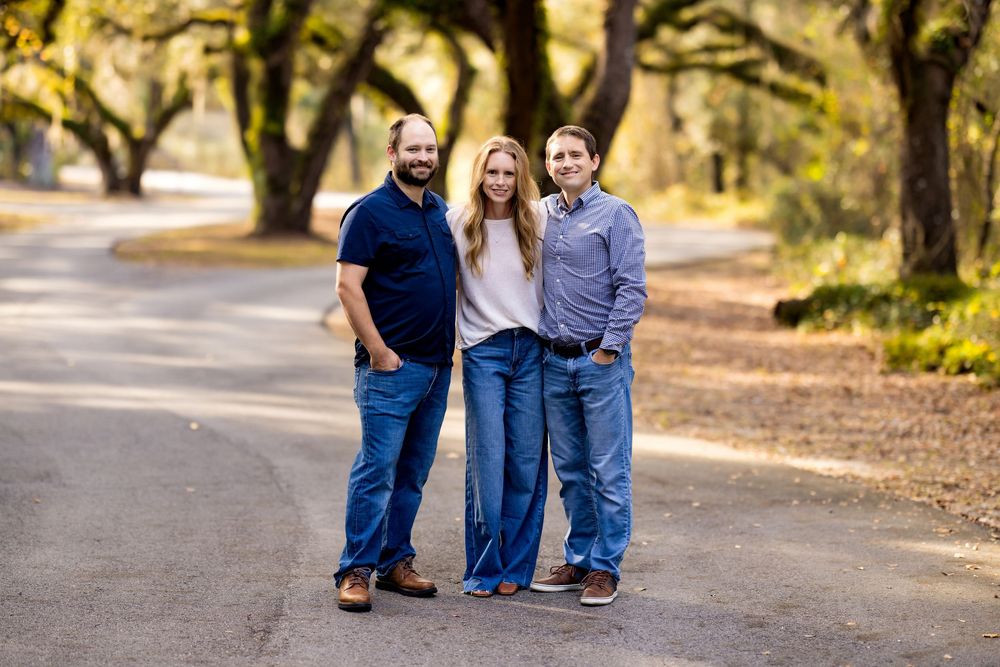 A group in casual blue outfits walks together on a tree-lined path during a sunny autumn day.