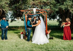 An outdoor wedding ceremony setup with wooden arch and white chairs arranged on grass under trees in Irrigon Oregon.