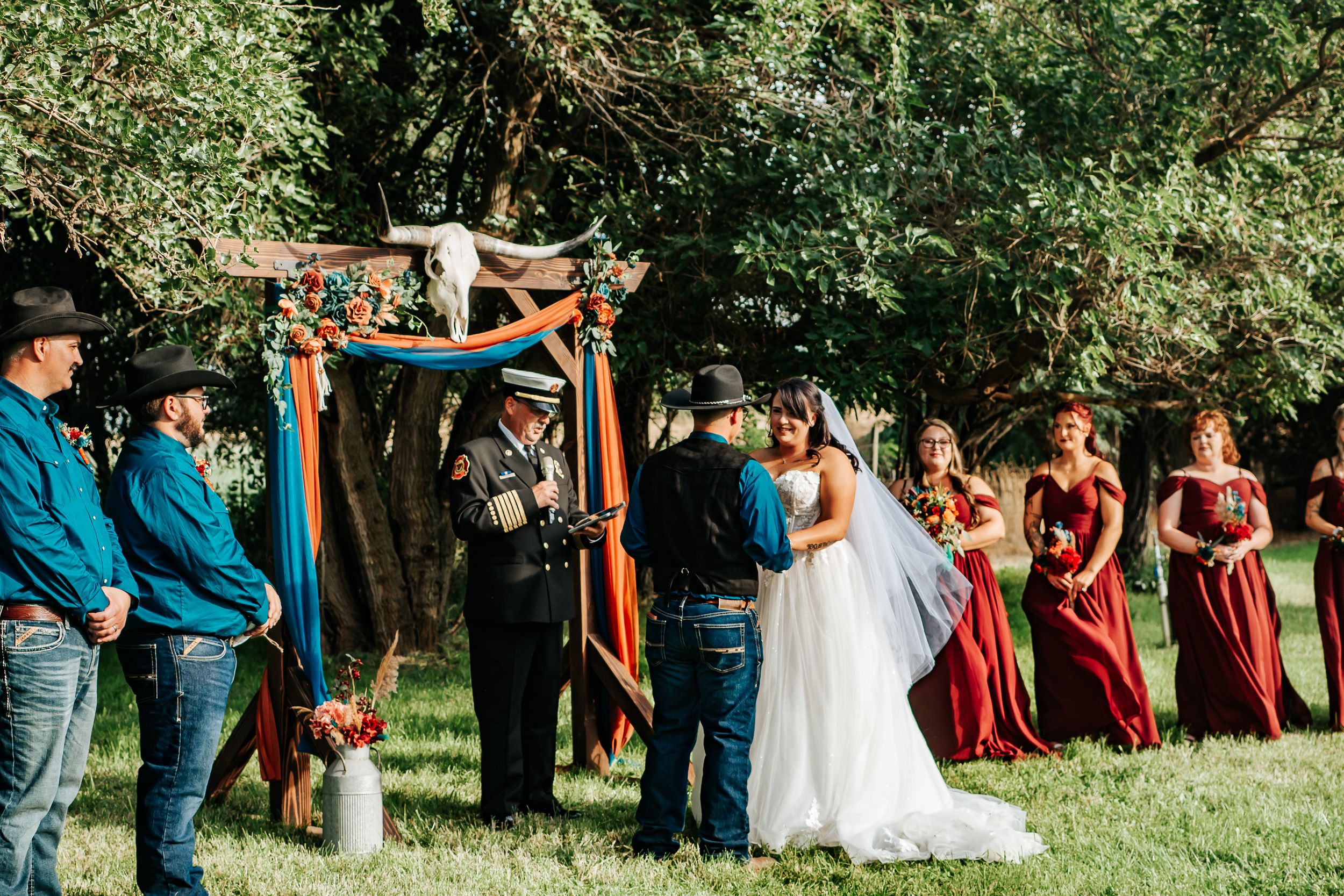 Wedding party stands in line outdoors with bridesmaids in burgundy dresses and groomsmen in navy suits in Irrigon, Oregon.
