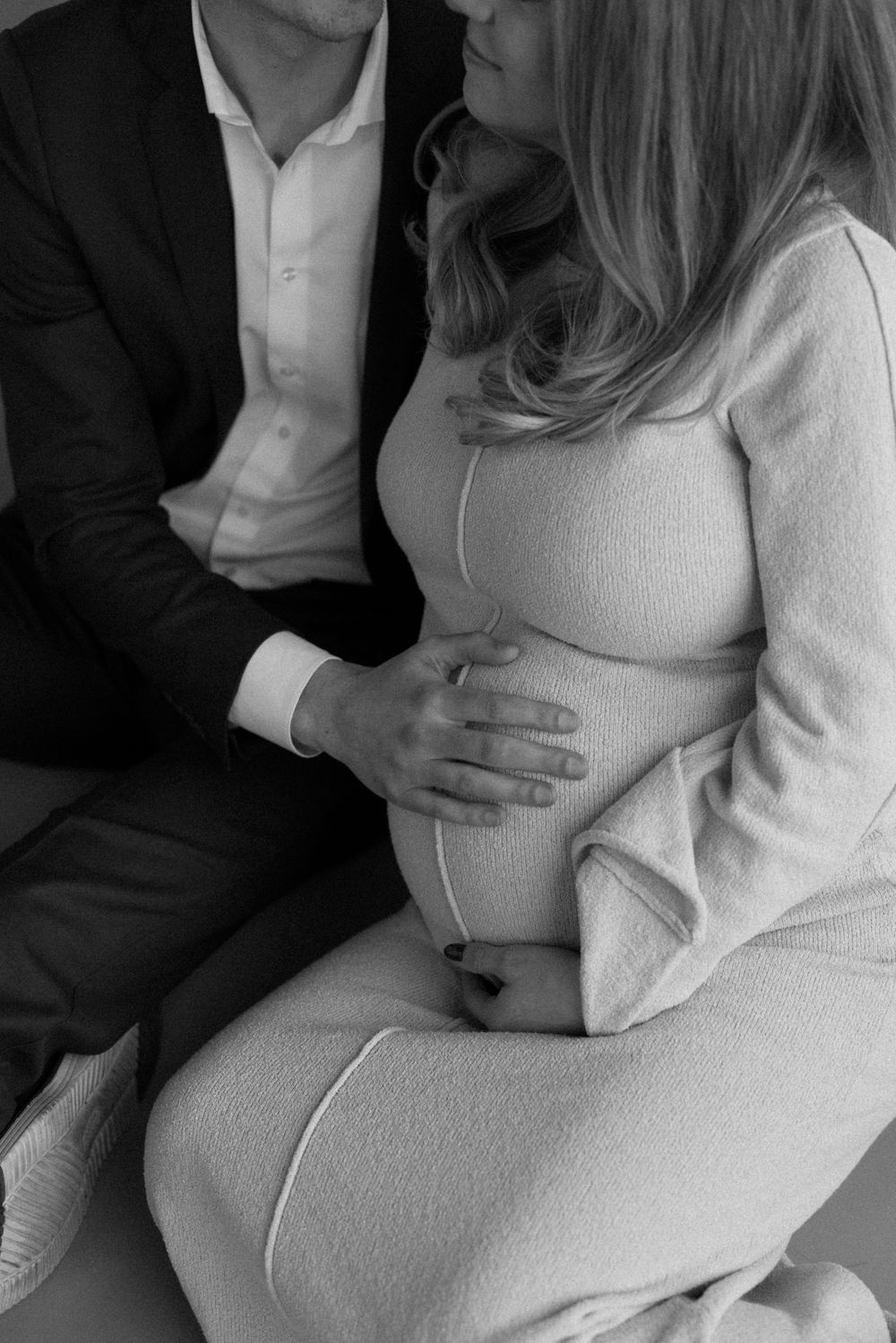 A series of black and white maternity photos showing a couple embracing with focus on the pregnant belly.