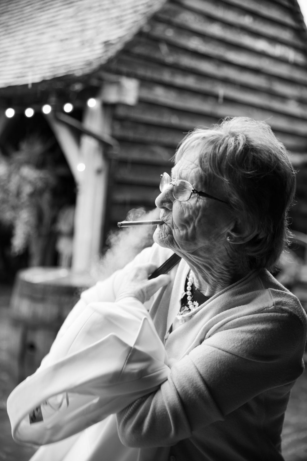 Black and white portrait of an elderly person smoking while wrapped in light fabric.