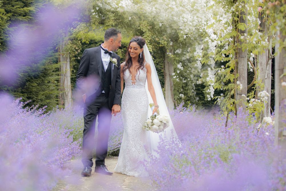 Couple poses in blooming lavender field during romantic wedding photoshoot.