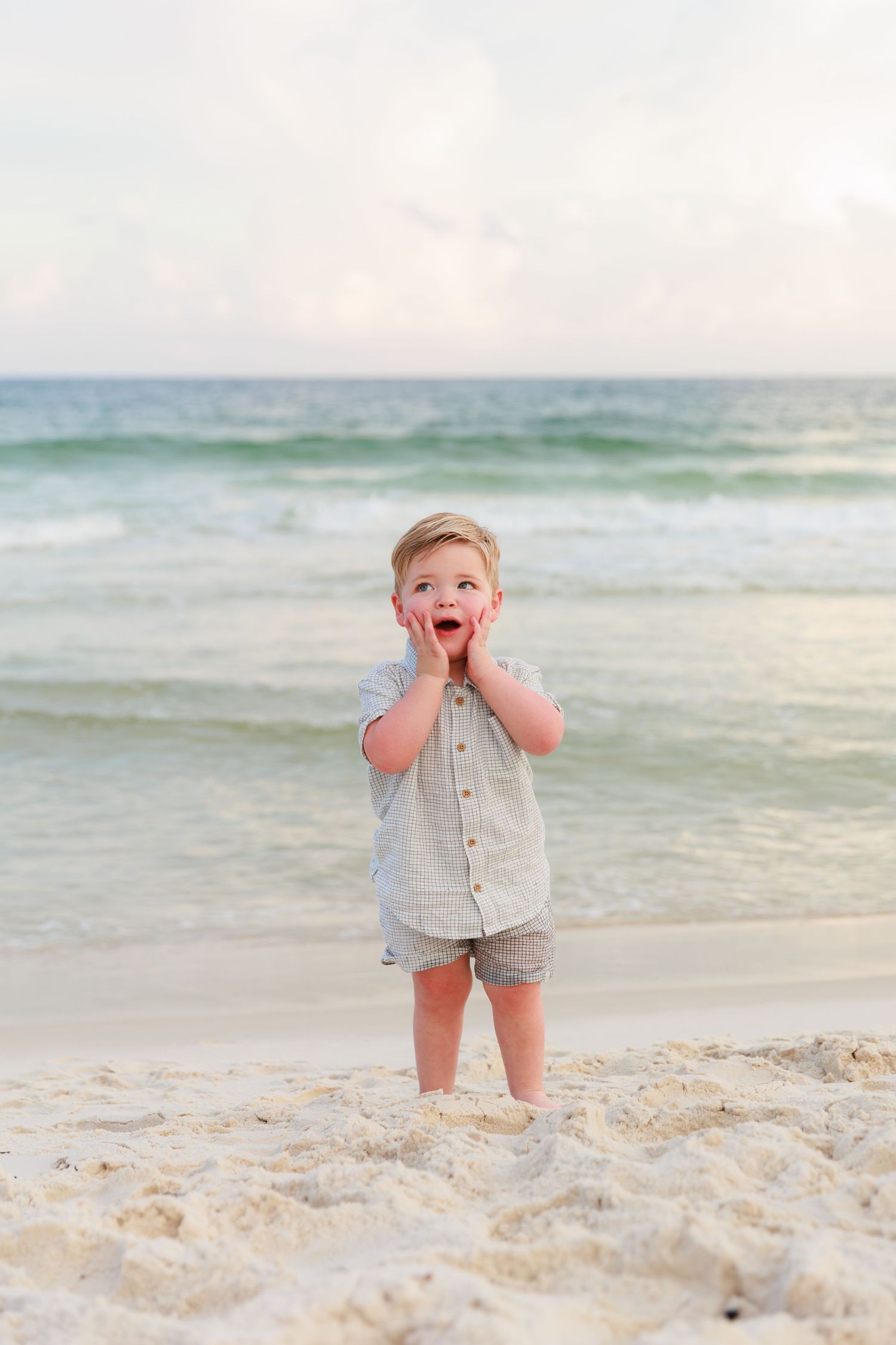 A joyful moment captured on a sunny beach with white sand and rolling waves in the background.