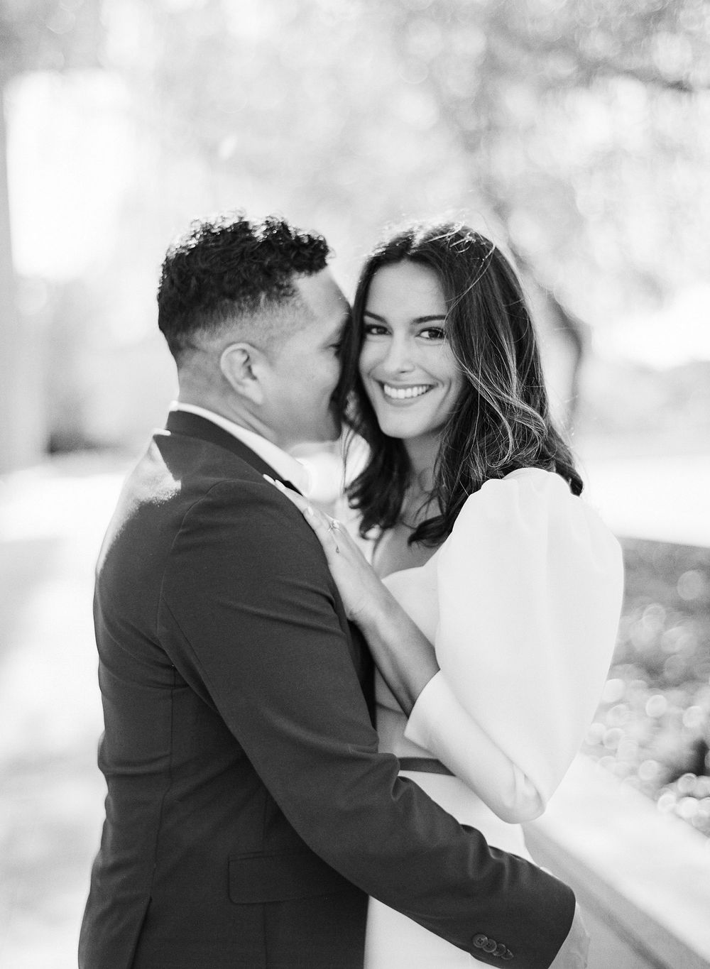 Black and white wedding photos show a romantic couple embracing and sharing intimate moments outdoors.