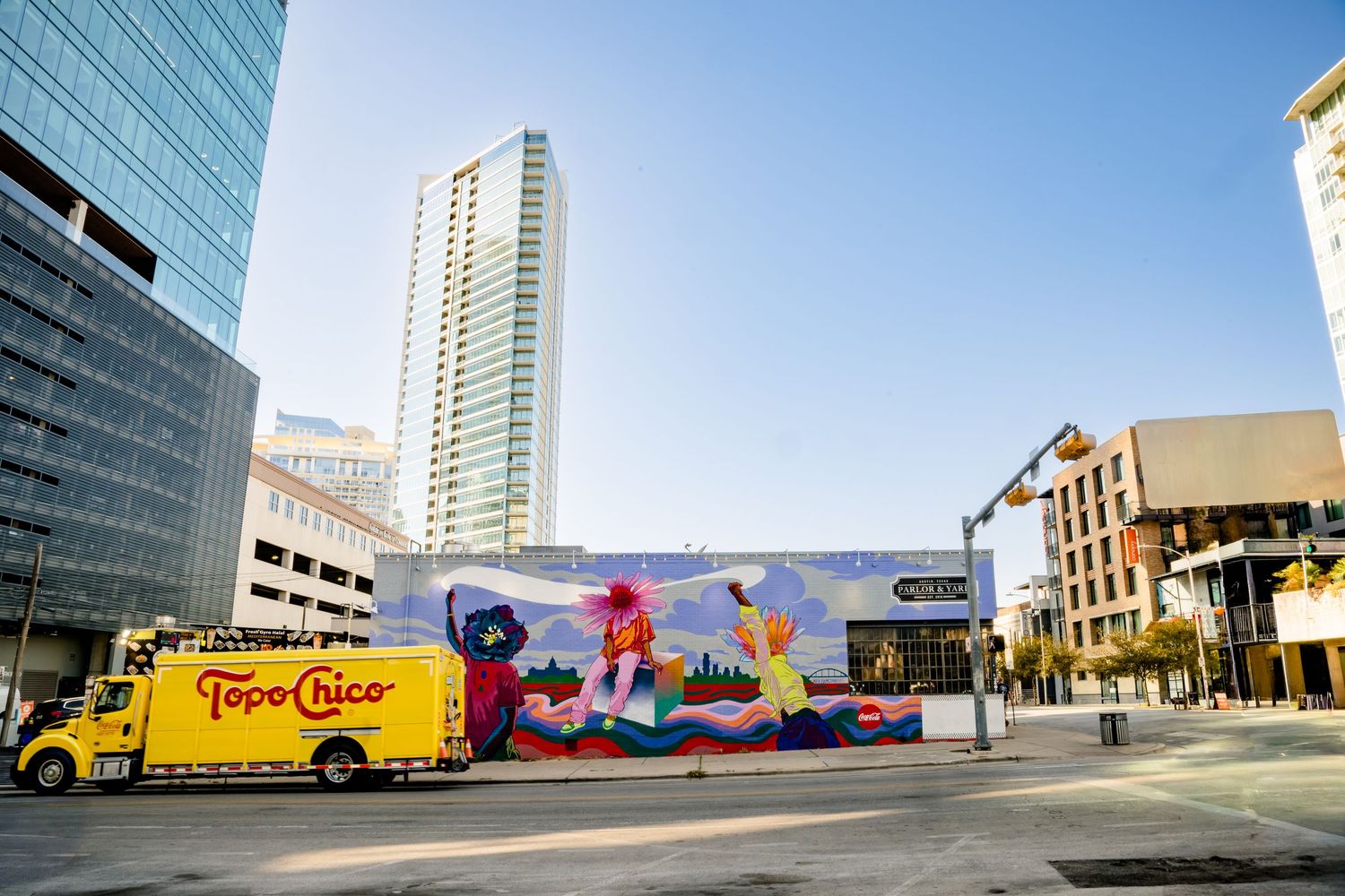 Row of delivery trucks and buildings lined up along a city street with high-rise buildings in the background.