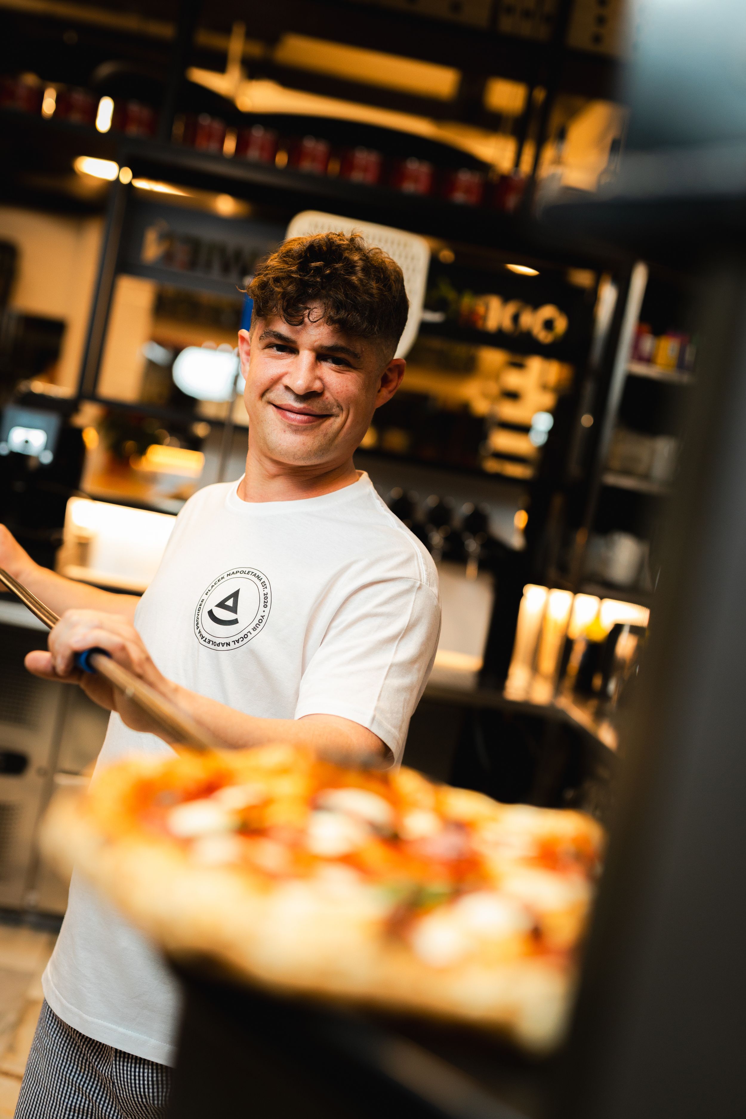 Pracownik prezentuje pizzę przed ladą restauracyjną. Fotografia biznesowa Lublin.