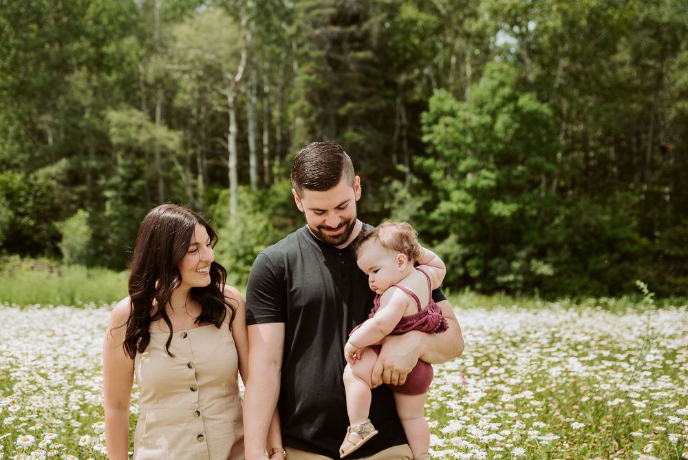 Family sitting together in a blooming wildflower meadow on a summer day.